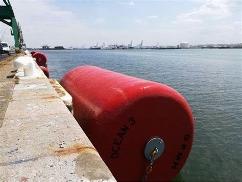 A large foam-filled boat fender floating alongside a dock, designed for heavy-duty vessel protection. This image highlights the durability and floatation capabilities of foam-filled fenders.