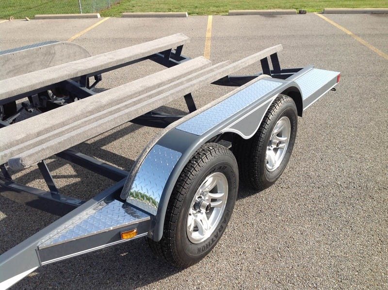 Boat trailer with dual axle and diamond plate aluminum fenders, designed for durability and corrosion resistance in wet environments.