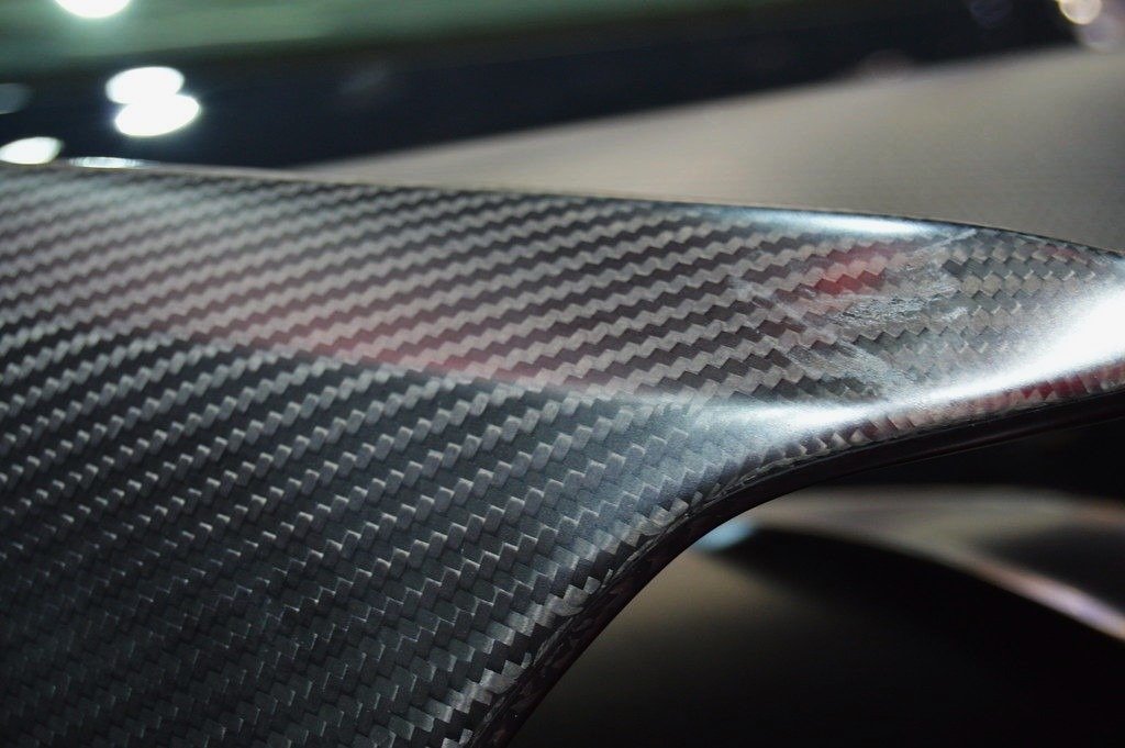 Close-up of a carbon fiber panel with visible woven pattern and surface imperfections