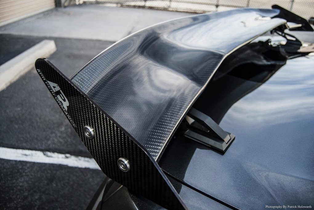 Close-up of a carbon fiber spoiler mounted on the rear of a car, showing its sleek, aerodynamic design