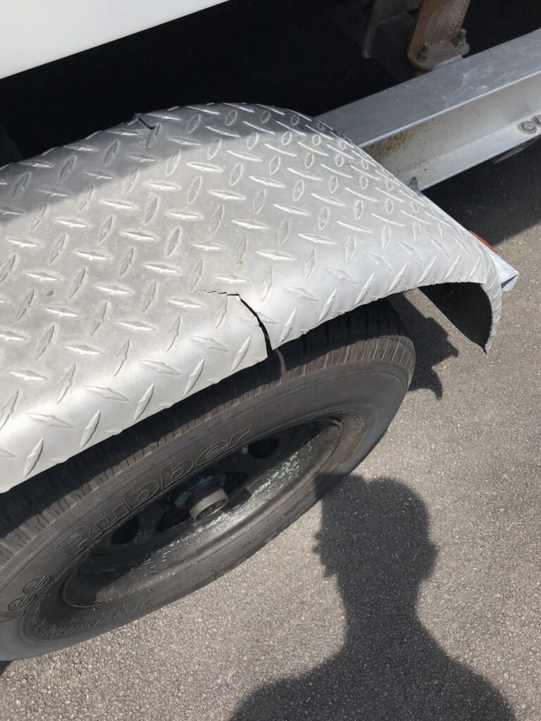 Cracked diamond plate steel trailer fender showing damage and wear, highlighting the potential need for repair or replacement