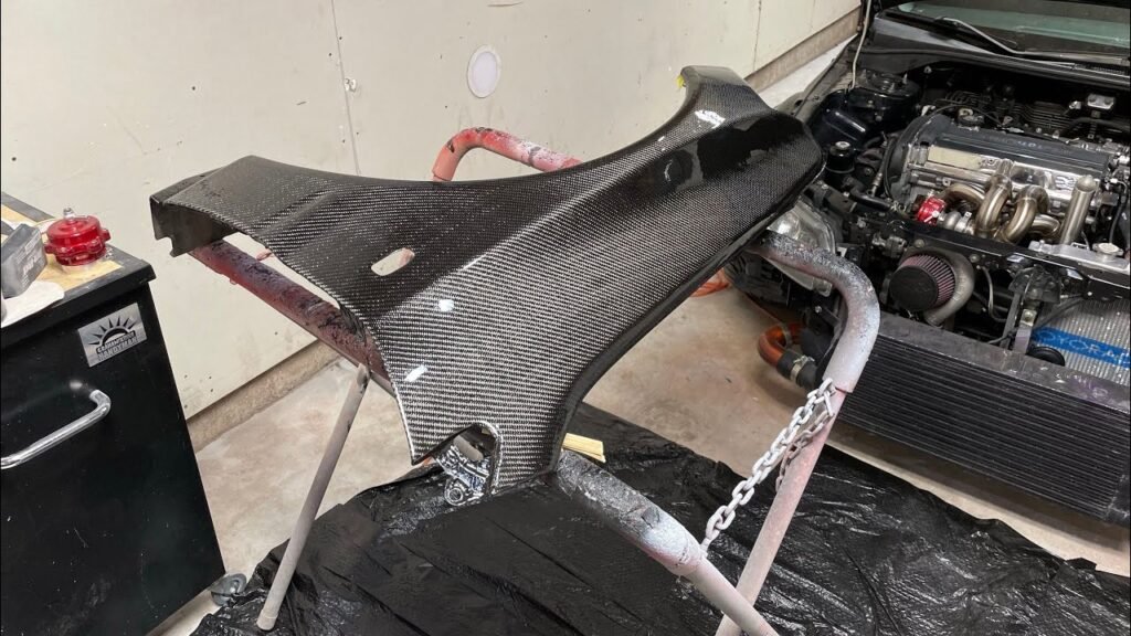 a carbon fiber fender being prepped on a stand in a garage