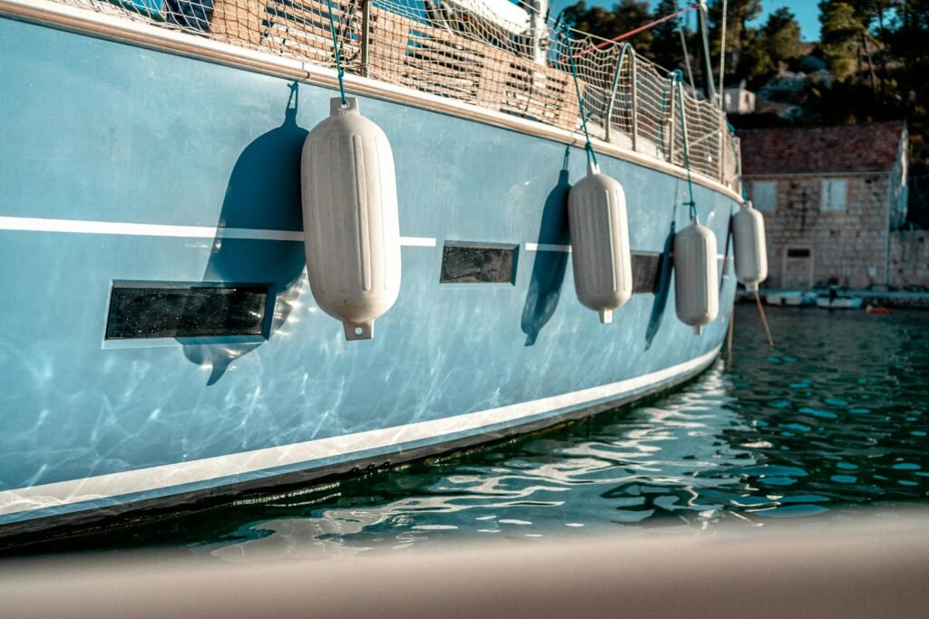 A well-secured red buoy fender on a black boat, demonstrating the correct method of how to tie fenders to a boat for optimal protection at the dock.