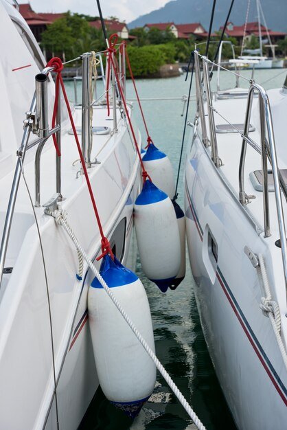 Cylindrical boat fenders hanging between two boats in a marina