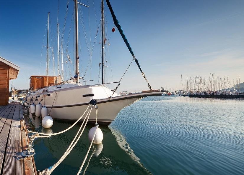 acht docked at a marina with fenders tied to the dock.